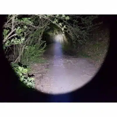 Klarus XT32 flashlight in hunting mode, illuminating distant game with 1200 Lumens beam in Kenyan wilderness.