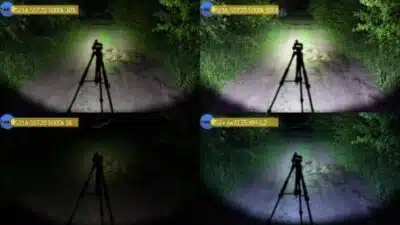 Convoy S21A flashlight casting 2300 lumens beam for night hiking trails in forested areas.