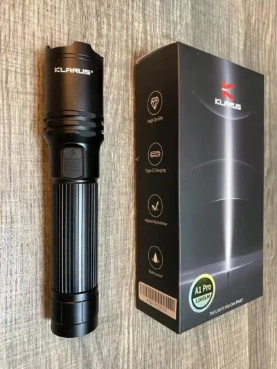Klarus A1 Pro flashlight with 1300 lumens for camping in Kenyan wilderness, illuminating trails up to 230 meters.